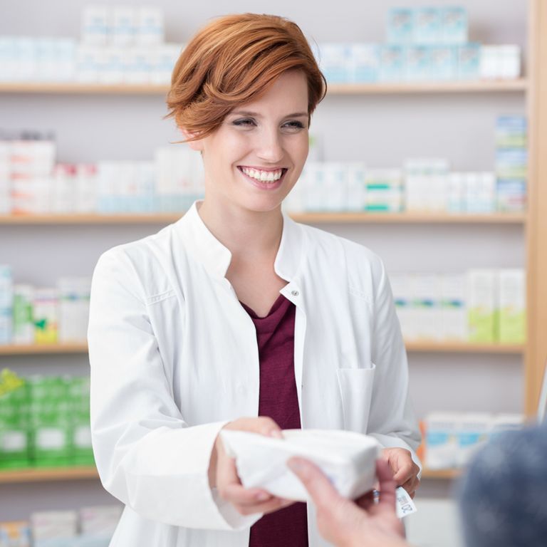 Zur Behandlung einer Blasenentzündung: FEMALAC® wird in der Apotheke von einer lächelnden Mitarbeiterin verkauft.
